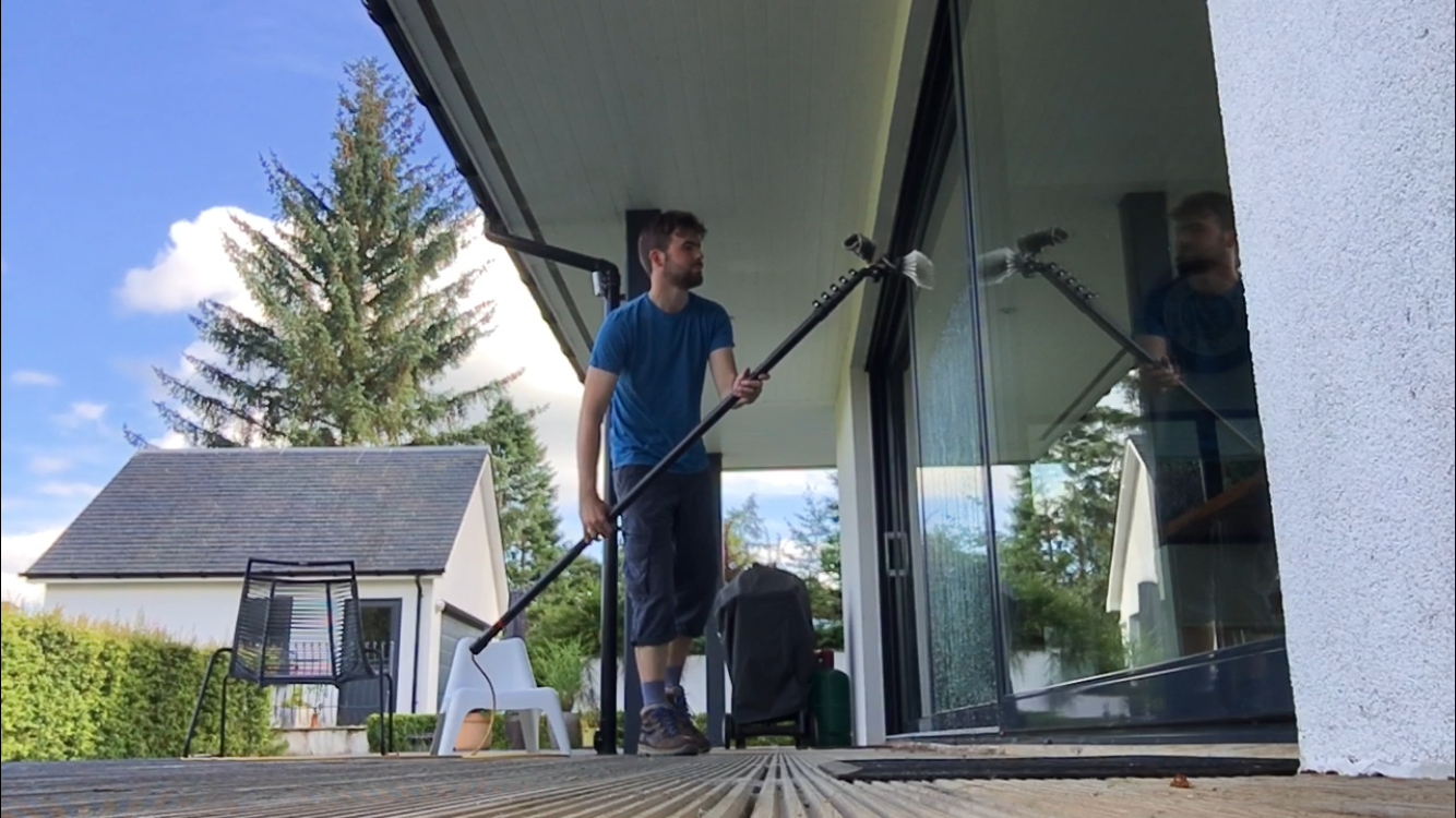 Nathaniel cleaning a wide sliding glass door from a deck