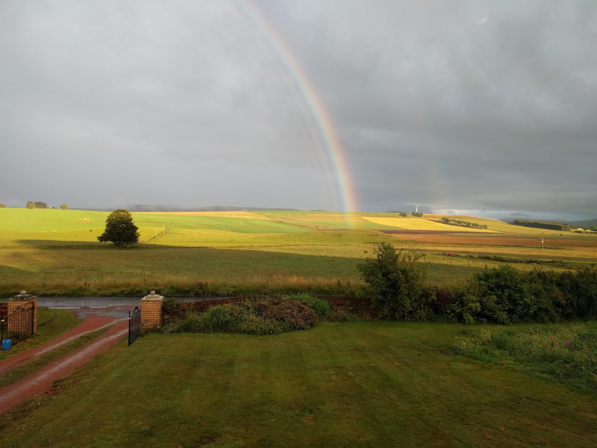 A rainbow over green fields, seen from a customer's garden